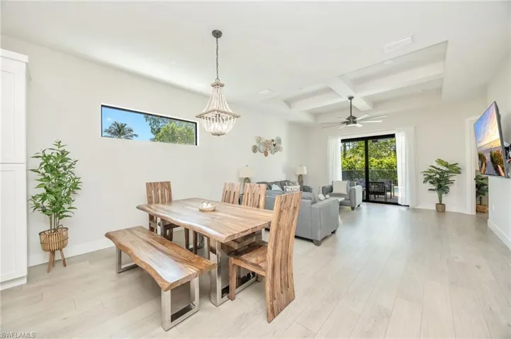 Open-concept living space featuring wood-finish flooring, a coffered ceiling with a built-in ceiling fan, and a transom window