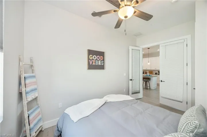 Room featuring wood-finish flooring, a ceiling fan with integrated lighting, and a white baseboard trim