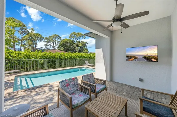 Covered patio featuring a ceiling fan, wall-mounted television, and paver flooring