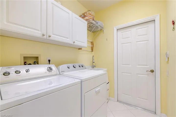 Laundry room with light tile patterned floors, cabinet space, and washing machine and dryer