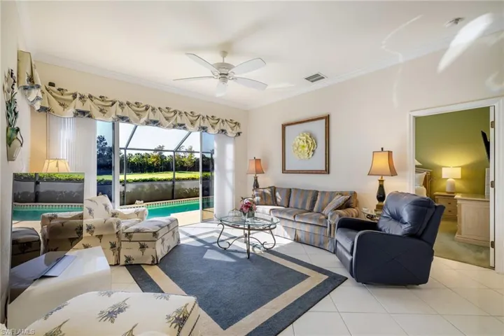 Living area featuring a sunroom, light tile patterned floors, ceiling fan, and crown molding