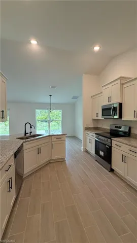 Modern kitchen featuring light cabinetry with dark hardware, granite countertops, and a stainless steel appliance suite