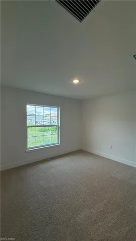Carpeted room with a recessed ceiling light and a window featuring horizontal muntins