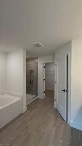 Modern bathroom featuring wood-look tile flooring, a built-in bathtub, and a glass-enclosed shower with subway tile surround