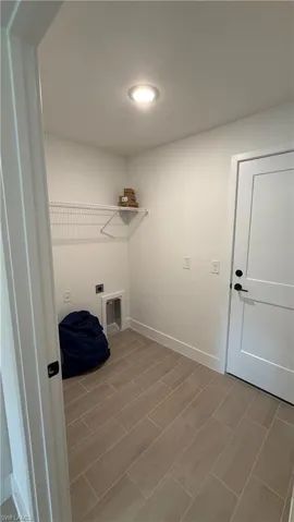 Utility room featuring wood-finish flooring, recessed lighting, and a wire storage shelf