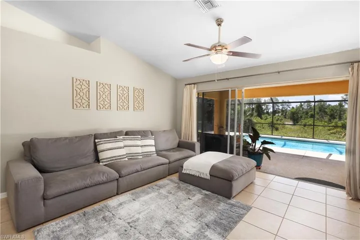 Living room with light tile patterned flooring, ceiling fan, and vaulted ceiling