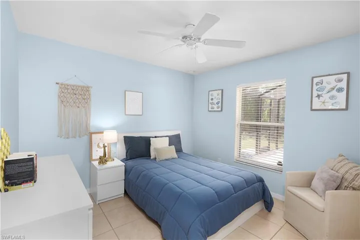 Tiled bedroom featuring ceiling fan overlooking pool