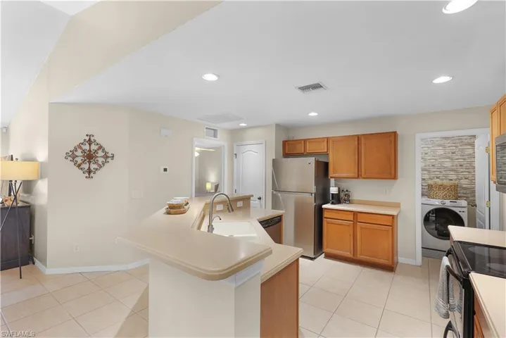 Kitchen featuring sink, stainless steel appliances, light tile flooring, and washer / dryer