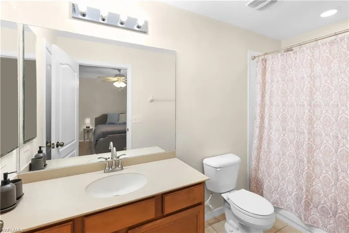 Bathroom with ceiling fan, oversized vanity, toilet, and tile floors