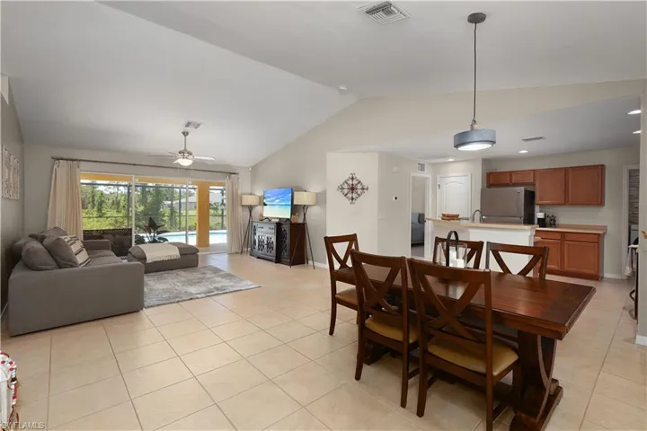 Dining space featuring vaulted ceiling, ceiling fan, and light tile flooring