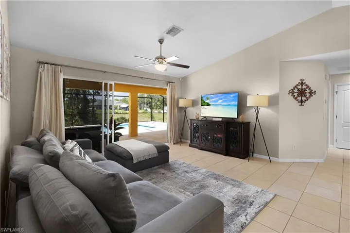 Tiled living room with lofted ceiling and ceiling fan