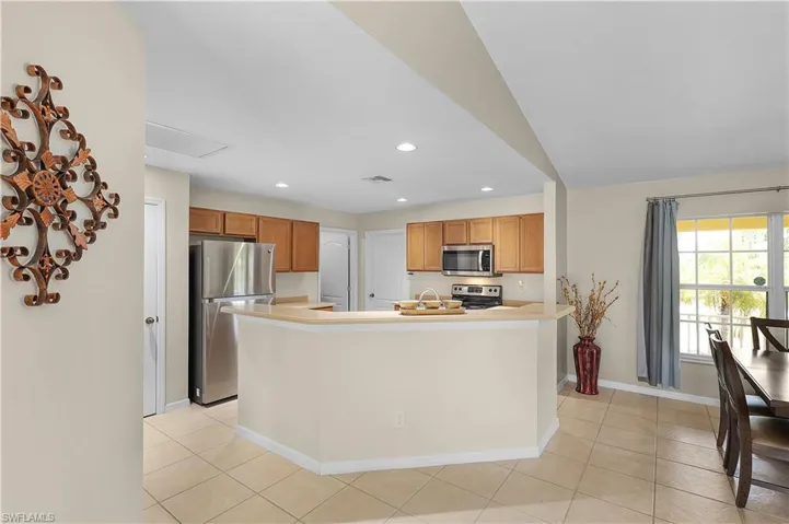 Kitchen featuring appliances with stainless steel finishes, sink, light tile floors, and lofted ceiling