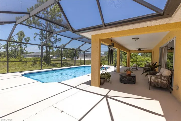 View of swimming pool featuring a patio, glass enclosure, an outdoor hangout area, and ceiling fan