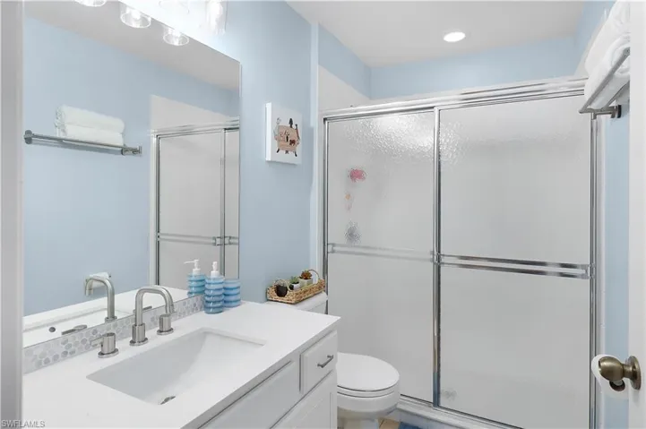 Bathroom featuring a shower with door, toilet, and vanity