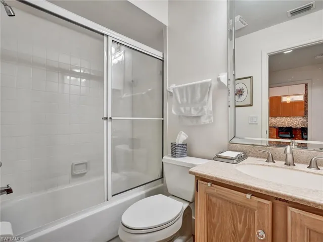 Full bathroom featuring combined bath / shower with glass door, vanity, and ensuite bath