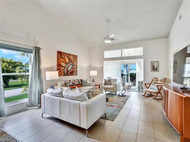 Tiled living room featuring high vaulted ceiling and ceiling fan