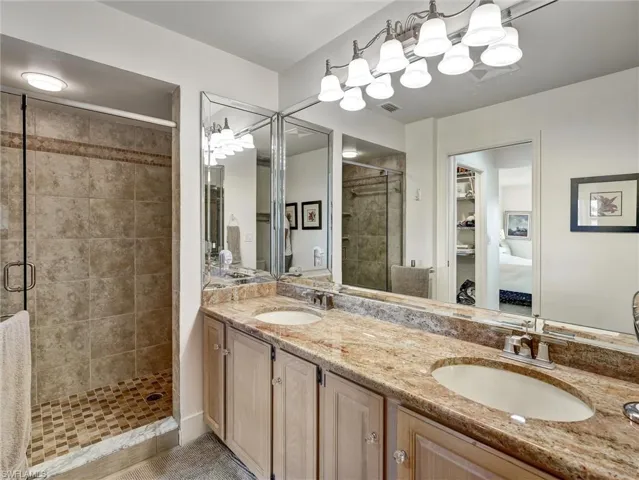 Ensuite bathroom featuring a stall shower, double vanity, and a closet