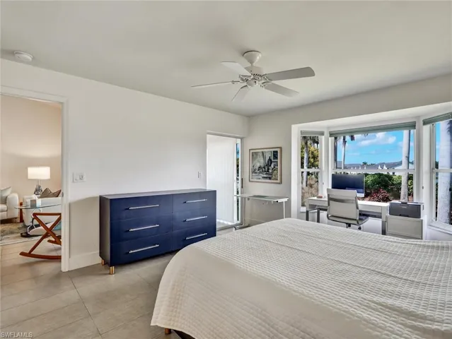 Bedroom with a ceiling fan, light tile patterned floors, and a desk