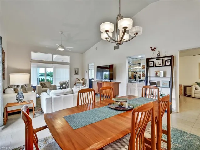 Dining room featuring a ceiling fan, light tile patterned floors, high vaulted ceiling, and a chandelier