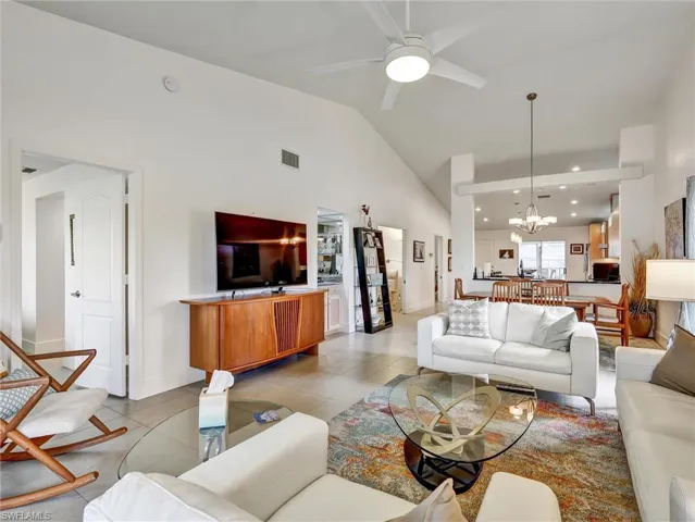 Living area featuring tile patterned flooring, ceiling fan, a chandelier, recessed lighting, and high vaulted ceiling