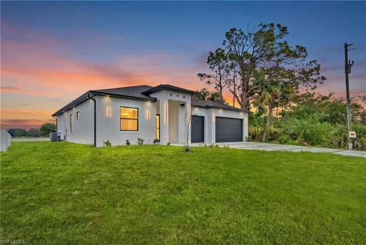 Modern exterior with white stucco finish, dark roof, and a three-car garage