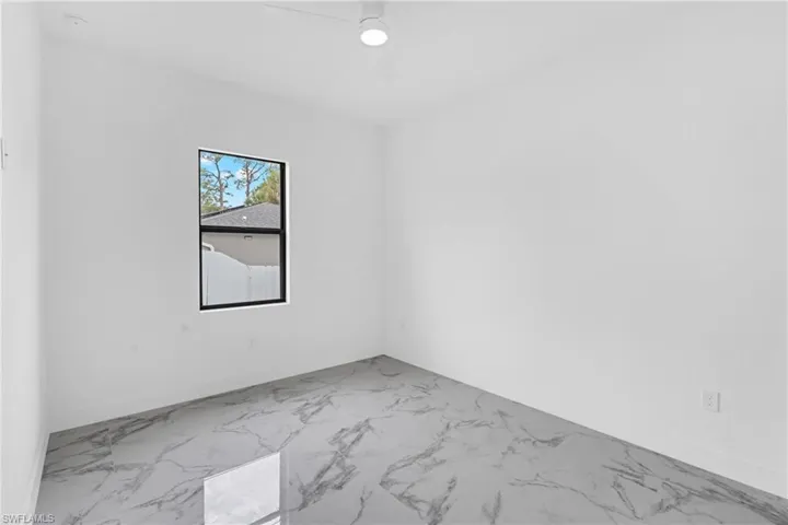 Bright interior space featuring a window with black trim, a ceiling fan, and large format tile flooring