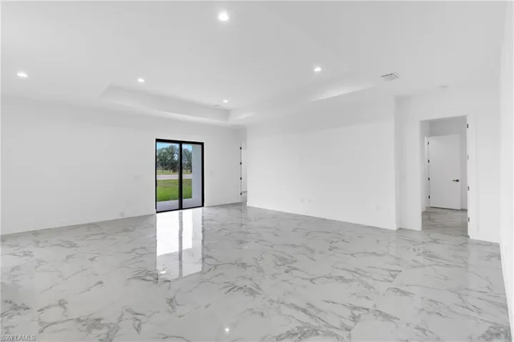 Spacious interior featuring large format marble-look tile flooring, crisp white walls, and a recessed ceiling design
