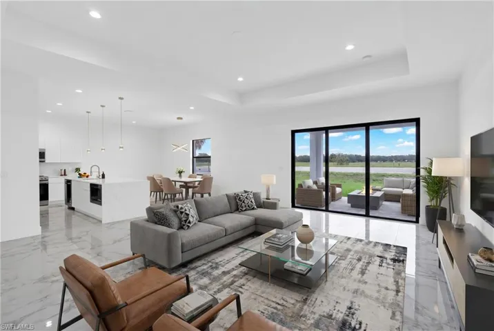 Virtually Staged.  Open-concept living area featuring large format white tile flooring and a tray ceiling