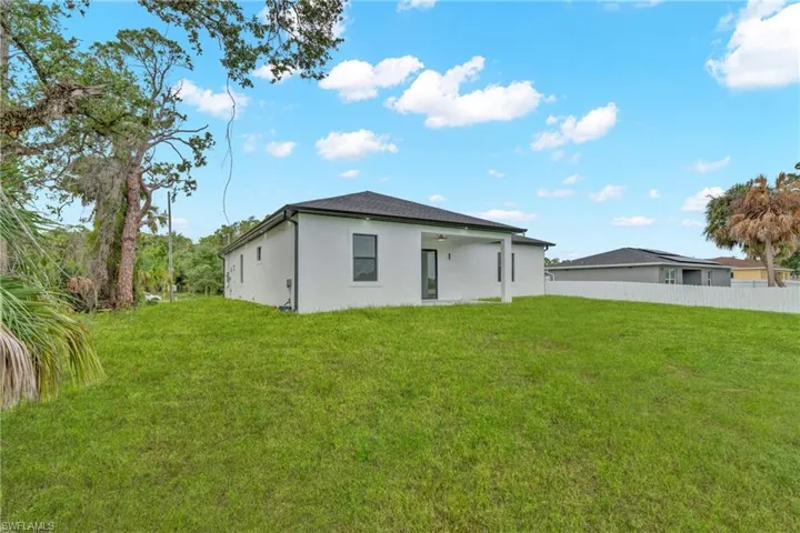 Expansive rear lawn featuring a modern single-story residence with white stucco exterior and dark framed windows