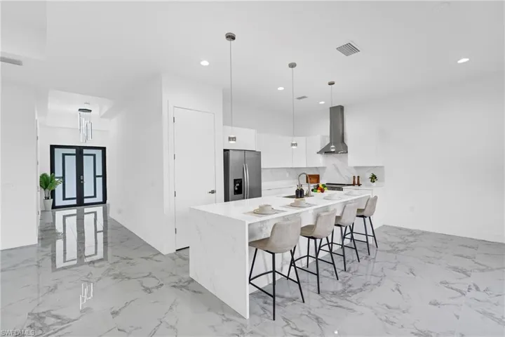 Kitchen featuring a waterfall-edge island with seating, stainless steel appliances, and ceiling-mounted pendant lighting