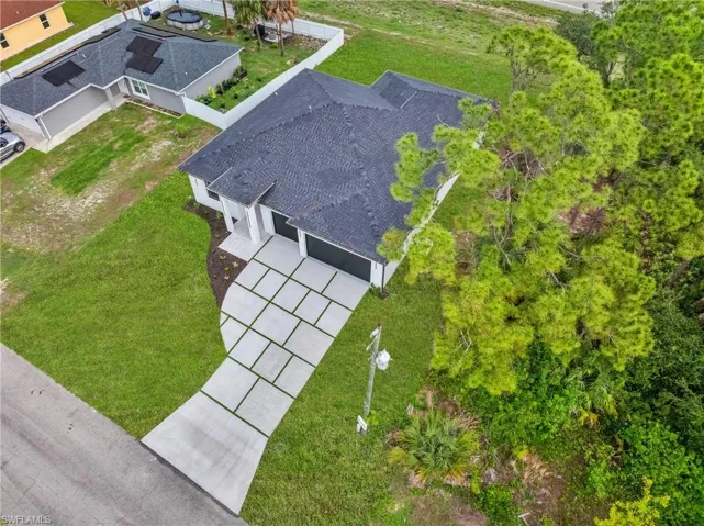Contemporary exterior featuring a dark asphalt shingle roof, attached three-car garage, and a paver-style driveway with accenting grass strips