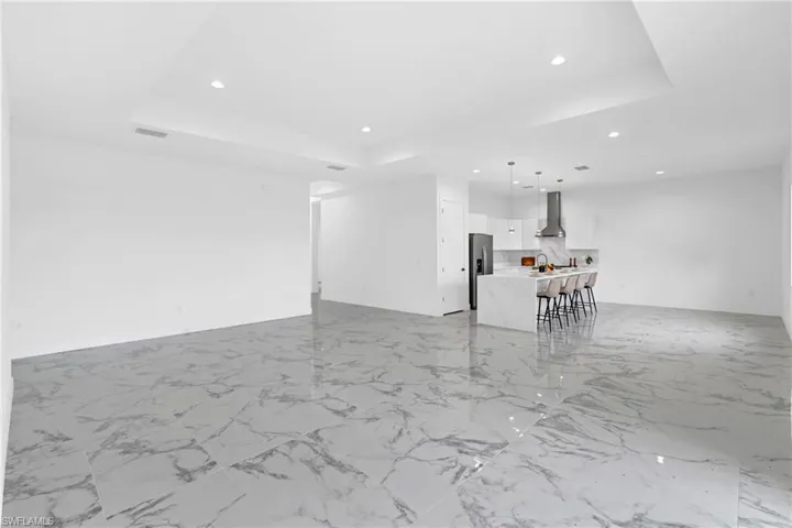 Open-concept kitchen and living area featuring large format marble-look tile flooring