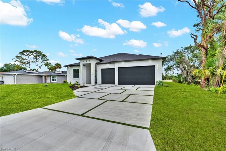 Modern exterior featuring a prominent three-car garage with dark paneled doors