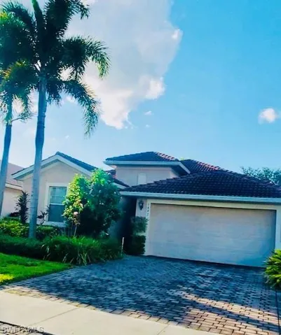View of front of property with decorative driveway, stucco siding, and an attached garage