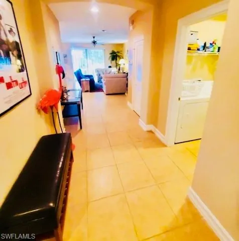 Corridor with washer / clothes dryer and light tile patterned floors
