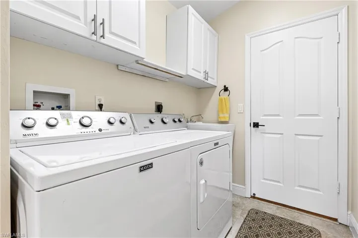Washroom with baseboards, cabinet space, washing machine and clothes dryer, and light tile patterned floors