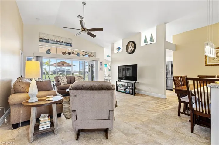 Living room featuring baseboards, visible vents, high vaulted ceiling, and a ceiling fan