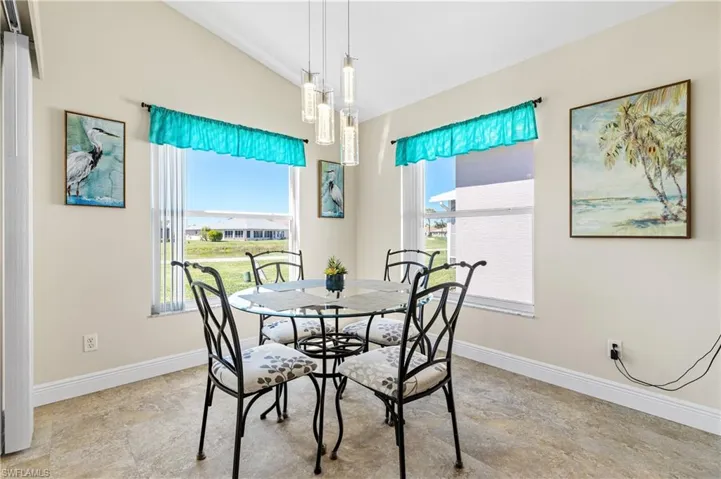 Kitchen breakfast area featuring a healthy amount of sunlight, baseboards, and vaulted ceiling