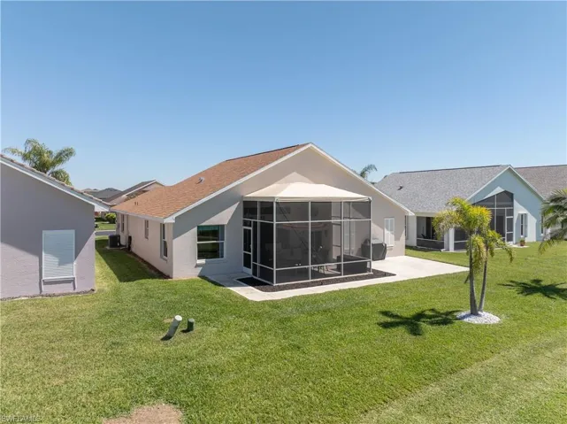 Back of house with a sunroom, stucco siding, a lawn, and a patio