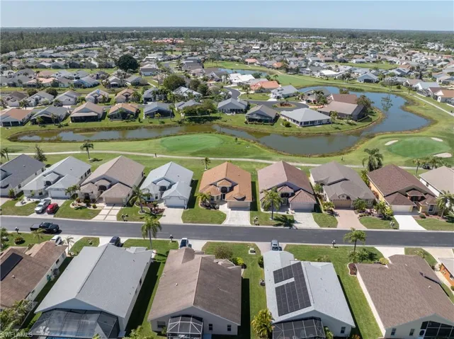 Drone / aerial view with a water view, view of golf course, and a residential view
