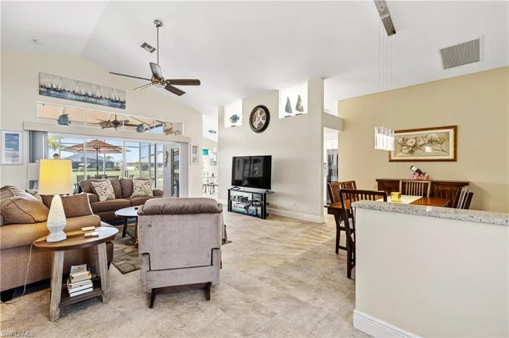 Living room with high vaulted ceiling, visible vents, ceiling fan, and baseboards