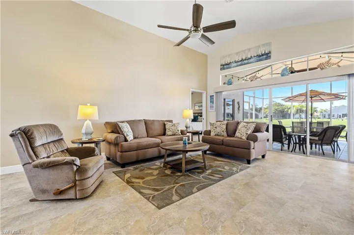 Living room with ceiling fan, high vaulted ceiling, a sunroom, and baseboards