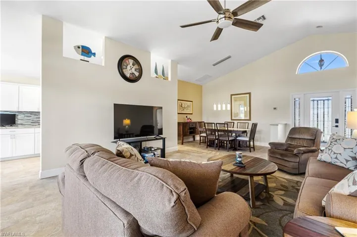 Living area with ceiling fan, visible vents, high vaulted ceiling, and baseboards