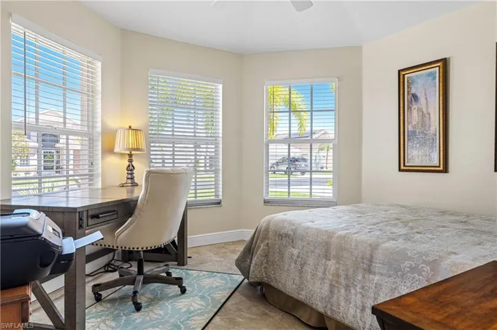 Bedroom with a ceiling fan, multiple windows, and baseboards