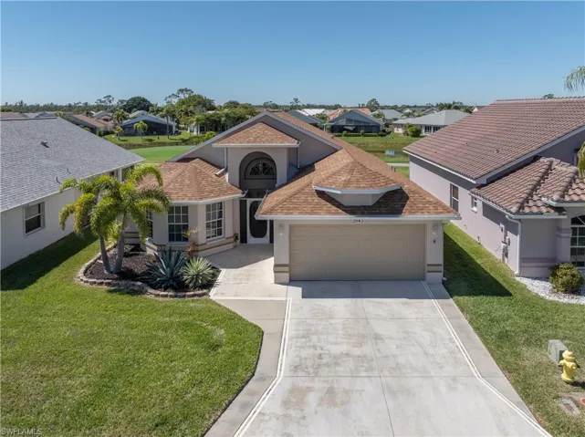 View of front of house with an attached garage, a front lawn, and stucco siding