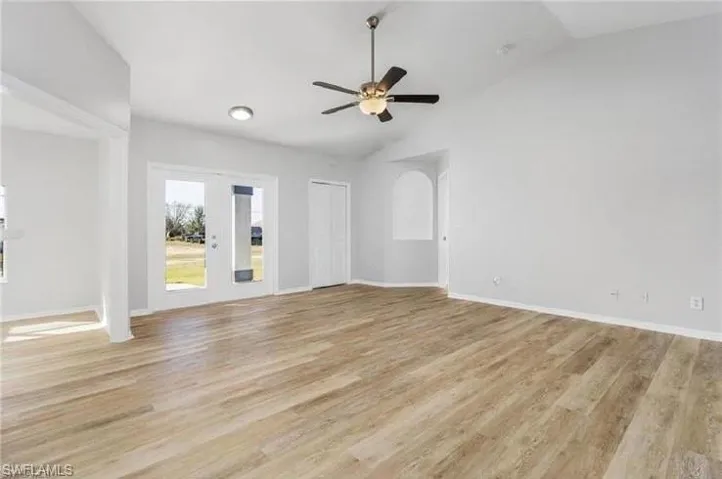 Spare room featuring french doors, light wood finished floors, lofted ceiling, and a ceiling fan