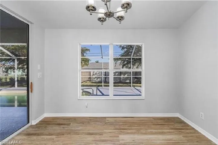 Unfurnished dining area featuring a chandelier, healthy amount of natural light, and wood finished floors