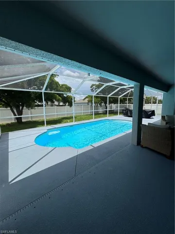 View of pool featuring a fenced backyard, a patio area, and glass enclosure