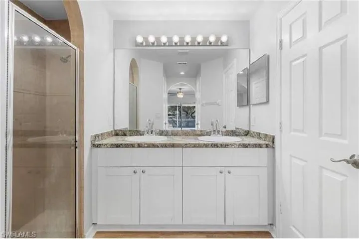 Full bathroom featuring a shower stall and double vanity