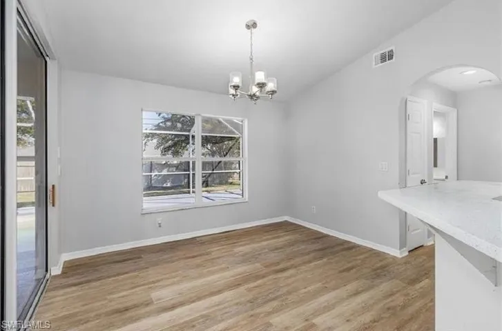 Unfurnished dining area with arched walkways, wood finished floors, and a chandelier